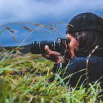 Retrato en plano medio de un fotógrafo sosteniendo su cámara réflex, ideal para ilustrar la fotografía básica.
