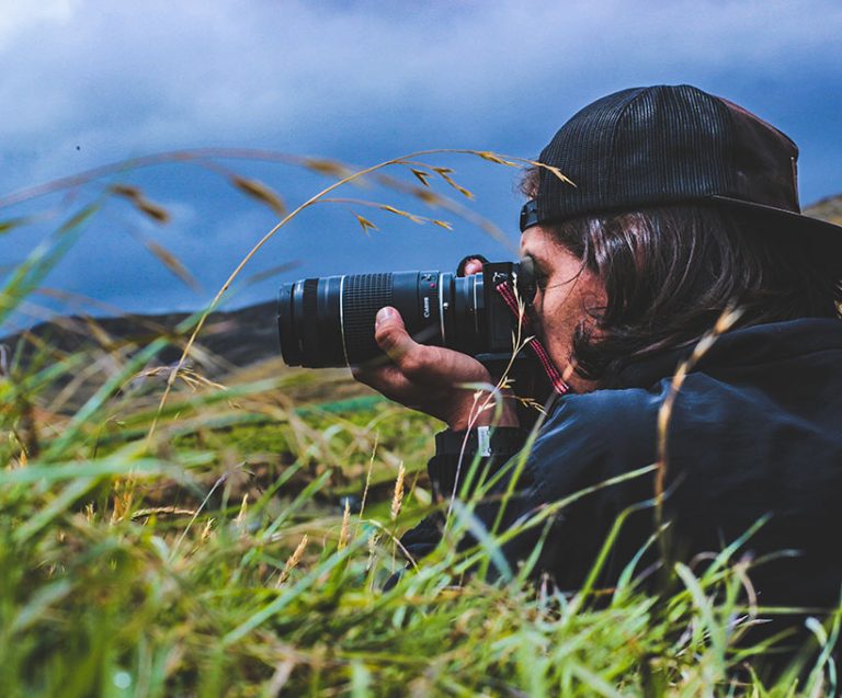 Dominando la Luz: Guía Definitiva sobre el Triángulo de Exposición 5 Retrato en plano medio de un fotógrafo sosteniendo su cámara réflex, ideal para ilustrar la fotografía básica.