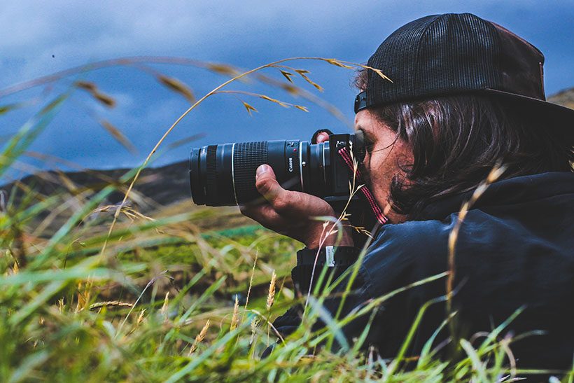 Dominando la Luz: Guía Definitiva sobre el Triángulo de Exposición 1 Retrato en plano medio de un fotógrafo sosteniendo su cámara réflex, ideal para ilustrar la fotografía básica.