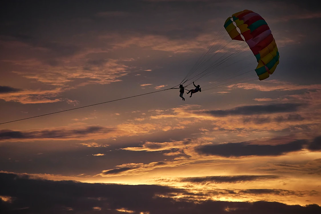 personas en parasailing en el atardecer
